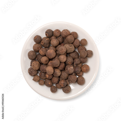 seeds of allspice in a white bowl on a white background