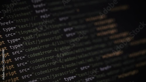 Website development. Closeup of HTML, CSS, JavaScript and PHP colorful code scrolling over dark background on computer screen photo