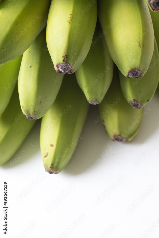 Layers of green and yellow baby bananas on white, copy space, vertical aspect