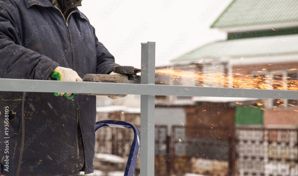 The worker cuts the metal with sparks The worker cuts the metal with sparks