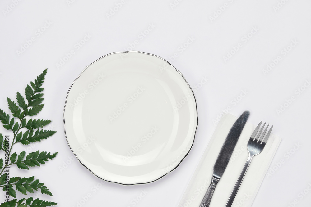 Dinner plate setting top view. Empty plate and silverware set on wooden table