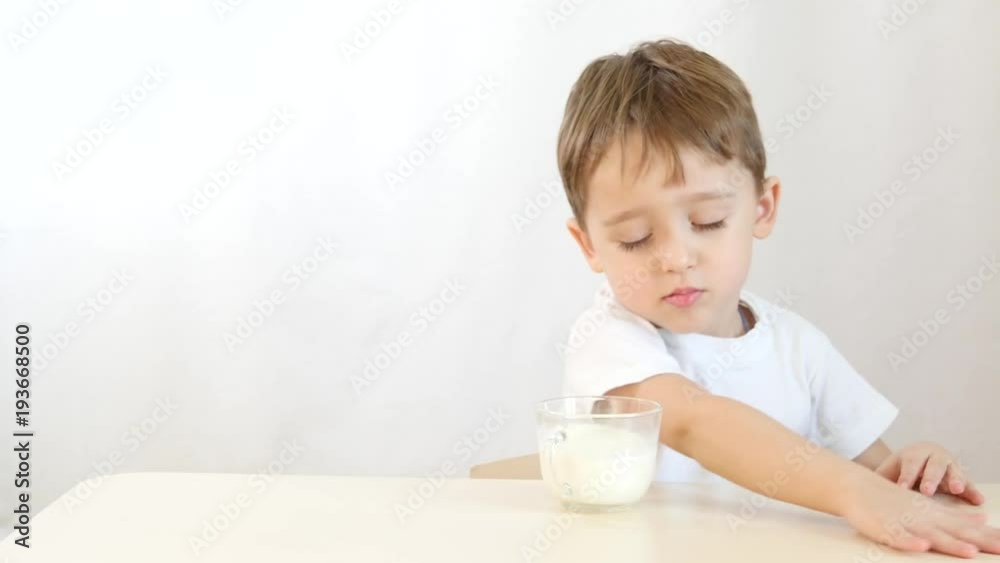 The child boy refuses to drink milk from the glass. Shooting on a white background. The child boy refuses to drink milk from the glass. Shooting on a white background.