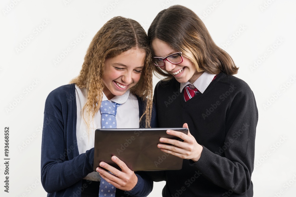Happy high school friends are teenage girls, look at the tablet and emotionally react Happy high school friends are teenage girls, look at the tablet and emotionally react