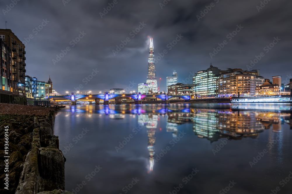 Blick auf die beleuchtete Skyline von London vom Ufer der Themse aus