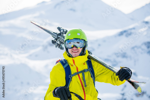 Portrait of sportive man in helmet with skis on his shoulder