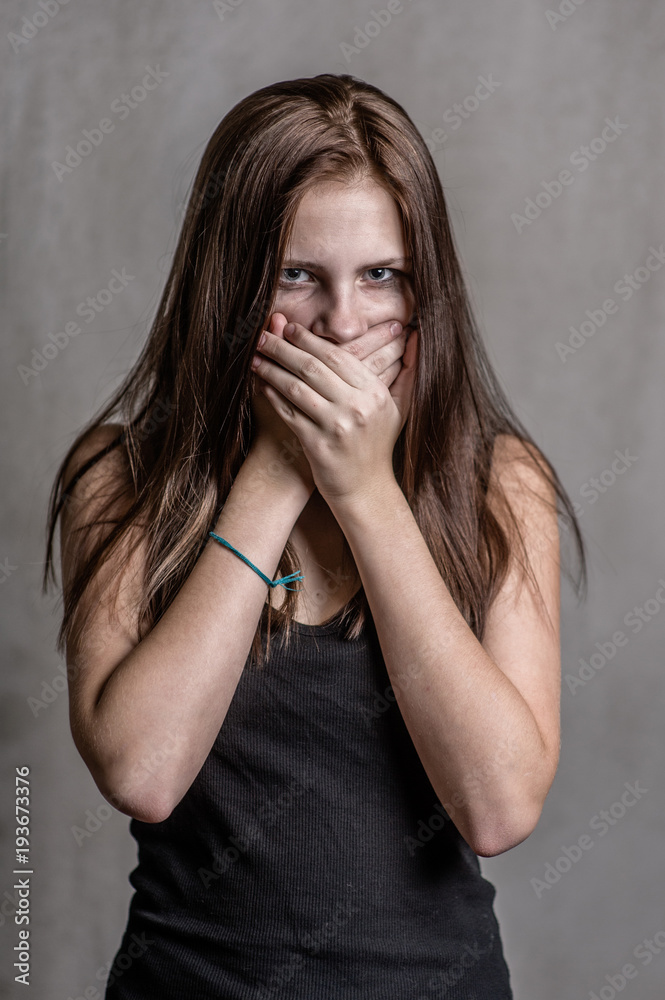 Frightened girl covers her mouth with her hands Frightened girl covers her mouth with her hands