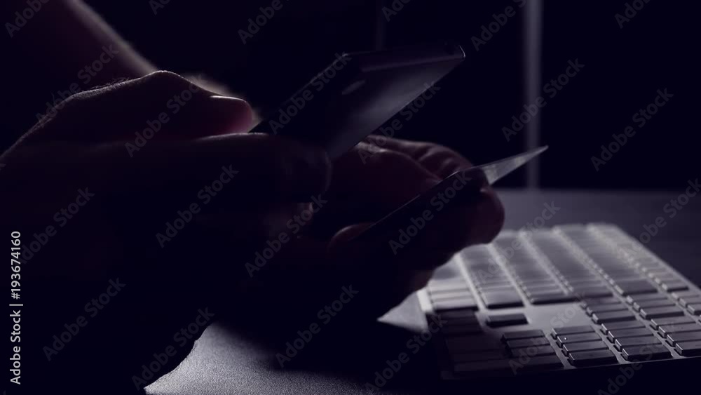 Mobile banking or m-banking concept, man using credit card and mobile phone app to make financial transaction online, low key footage