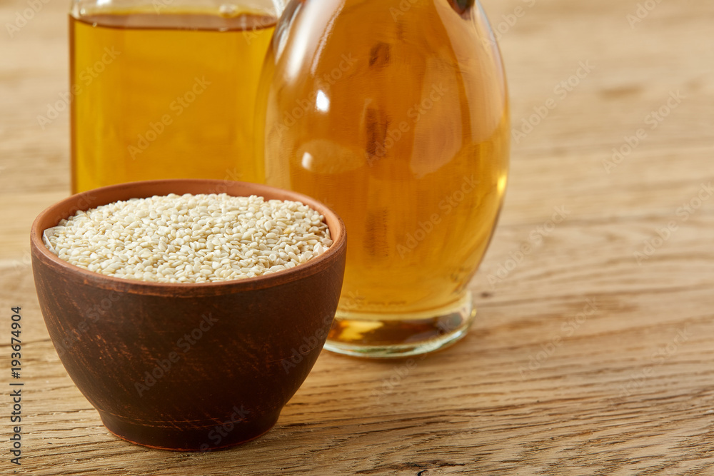 Kitchen still life of glass oil jars and bowl with sesam on wooden background, shallow depth of field, selective focus Kitchen still life of glass oil jars and bowl with sesam on wooden background, shallow depth of field, selective focus