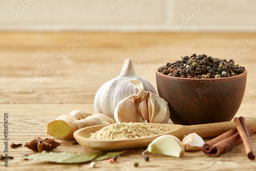 Composition of powder spices on spoon and different sorts of spicies on wooden table background, selective focus photo