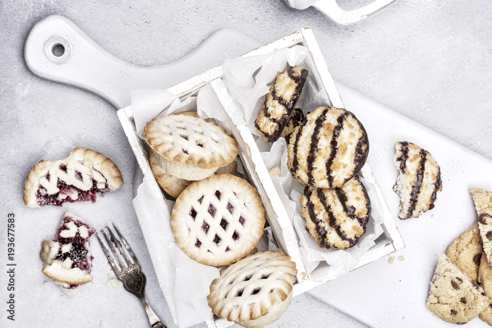 Assortment of pies and cookies on a light gray rustic background. Assortment of pies and cookies on a light gray rustic background.