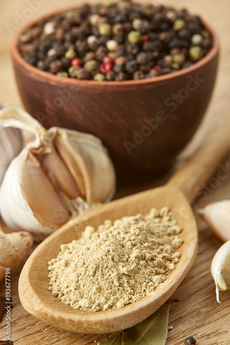 Composition of powder spices on spoon and different sorts of spicies on wooden table background, selective focus