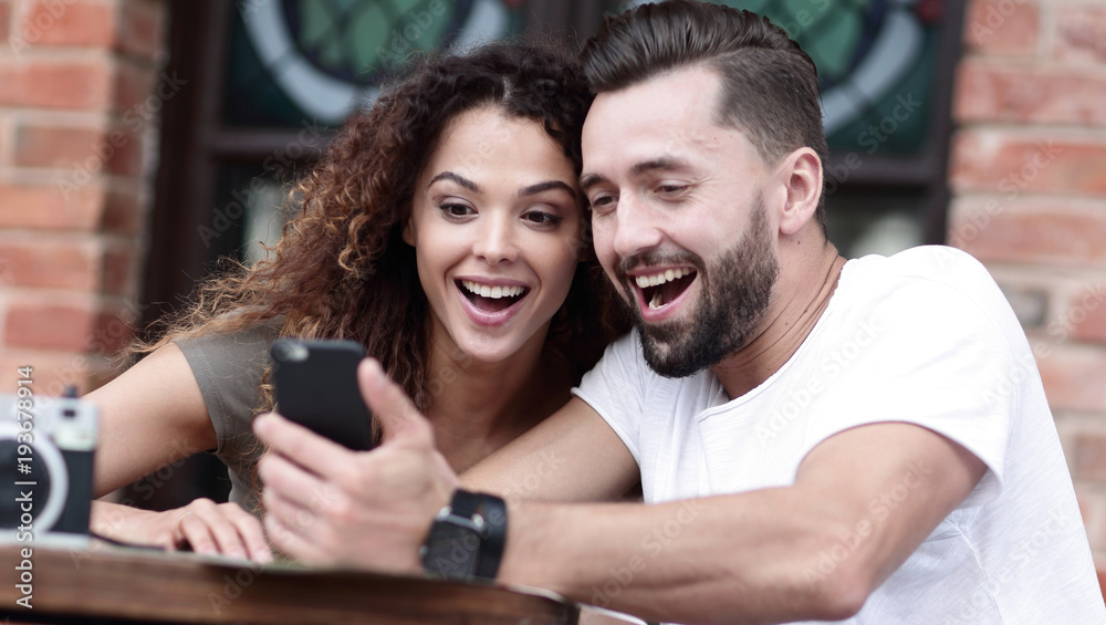 Portrait of a young couple sitting down at a cafe terrace Portrait of a young couple sitting down at a cafe terrace