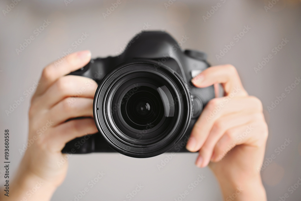 Female photographer holding camera on blurred background