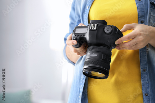 Female photographer holding camera indoors