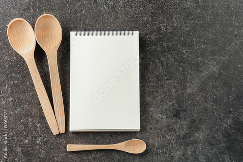 Notebook and wooden spoons on grey background. Cooking master classes