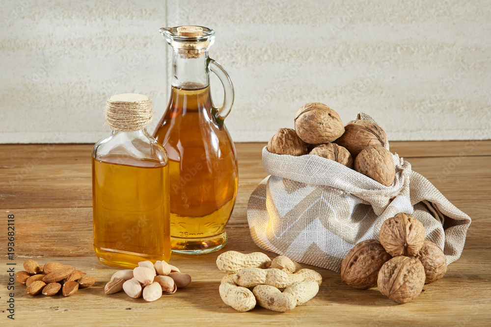 Conceptual composition of glass oil jars with different kinds of nuts on wooden table, close-up. Conceptual composition of glass oil jars with different kinds of nuts on wooden table, close-up.