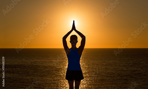 A girl practicing yoga in a sunset