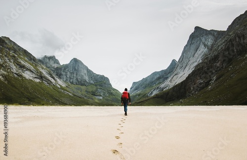 Man with backpack walking away alone at sandy beach in mountains Travel lifestyle concept adventure outdoor summer vacations in Norway wild nature photo