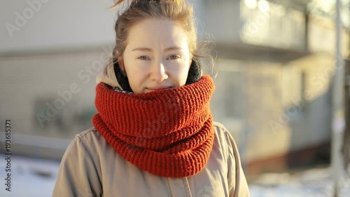 Calm peaceful happy girl with stylish knitted sarf looking at the camera outside on the sunny snowy street. portrait winter holidays Christmas vacation relax walk stroll sun rays sunshine fashion photo