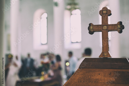 Fotografia Wedding event in a church the old wooden cross is in a first view and the people