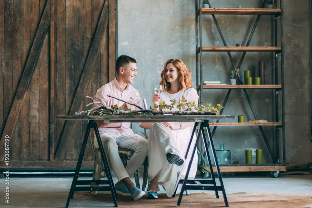 Portrait of young happy couple with glasses at table