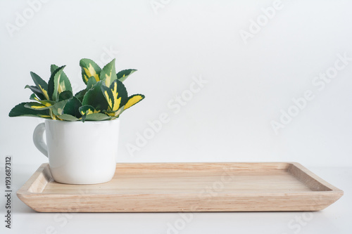 Bamboo tray with white coffee mug and yellow-green leaves and a scented candle