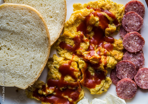 Scrambled eggs with ketchup with bread, salami  and cheese