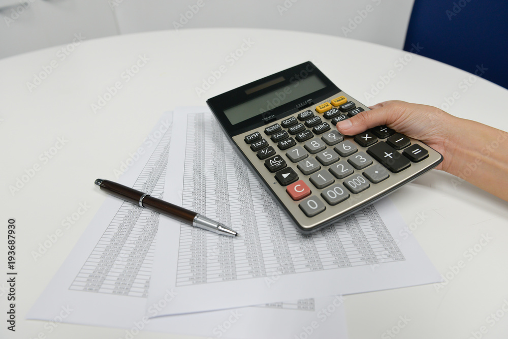 Woman hand is using the calculator to calculate the finance document Woman hand is using the calculator to calculate the finance document