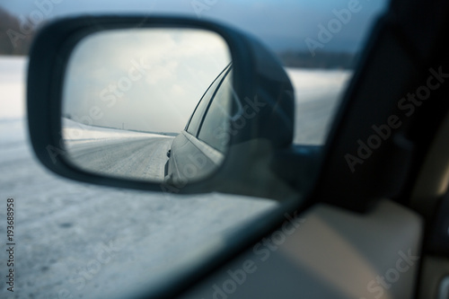Rear view mirror of a modern car on a winter day(shallow DOF; color toned image)