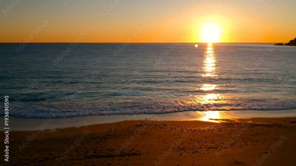 Aerial view travelling along a golden beach towards the sea on a beautiful sunset Aerial view travelling along a golden beach towards the sea on a beautiful sunset