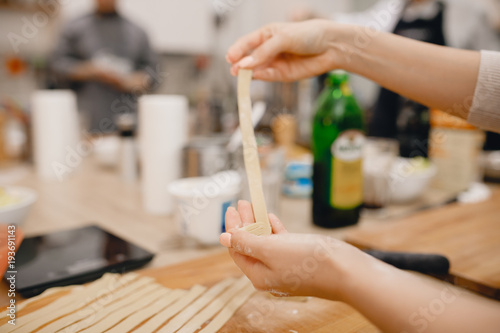 Girl cuts the dough for making Italian pasta