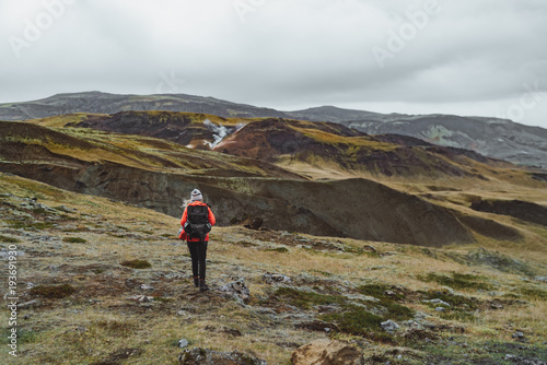 One woman wanders in Iceland with backpack in a red jacket