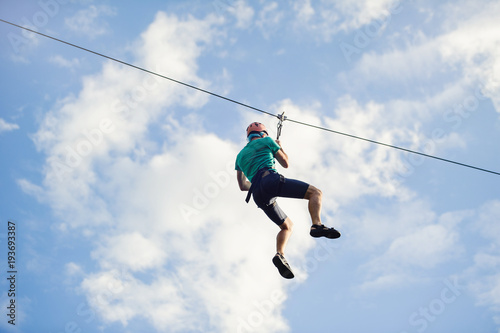 a man descends on a rope, a sport in an extreme park, A man walking along a zip line