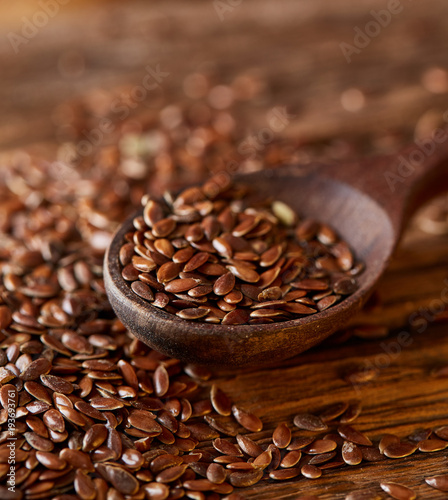 Wooden spoon with flax seeds on rustic background, top view, close-up, shallow depth of field, selective focus