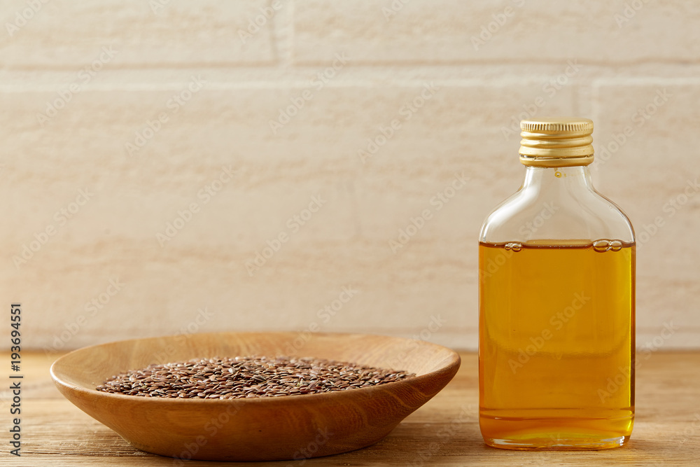 Flax seeds in bowl and flaxseed oil in glass bottle on wooden background, top view, close-up, selective focus Flax seeds in bowl and flaxseed oil in glass bottle on wooden background, top view, close-up, selective focus