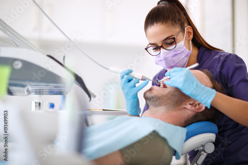 Fototapeta Naklejka Na Ścianę i Meble -  Dentist drilling tooth to male patient in dental chair