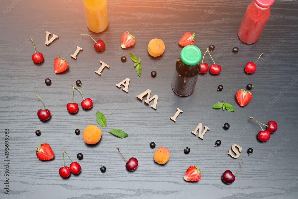 Bottles of juice, the inscription Vitamins and fruits. Wooden background.