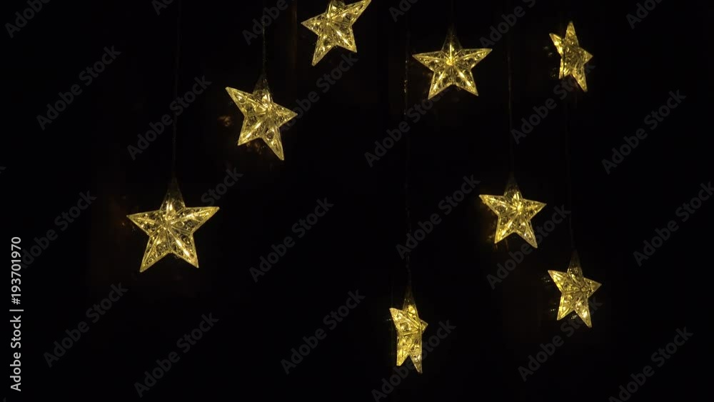 Shiny decorative stars hang at a black window - closeup Shiny decorative stars hang at a black window - closeup