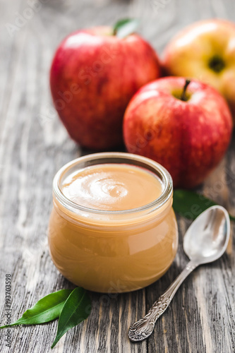 Photos Healthy sugar free applesauce in glass jar and red ripe apples on rustic wooden background