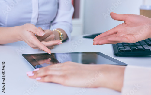 Woman touching digital tablet hand. Young business crew working with new startup. Horizontal closeup photo.