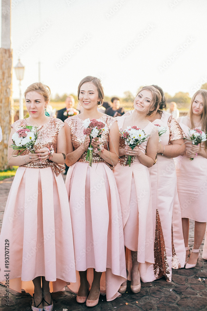 Row of bridesmaids with bouquets at wedding ceremony. Beautiful girls in the same dress.