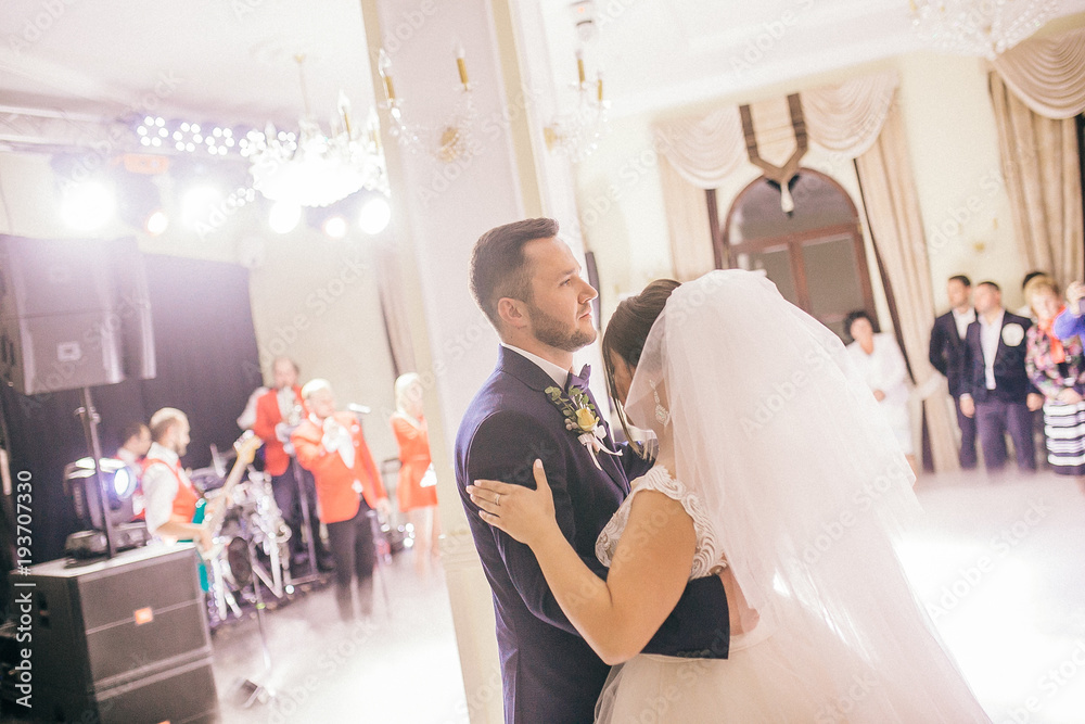 Wedding of beautiful caucasian couple just married and dancing their first dance. Bride and groom in wedding restaurant hall