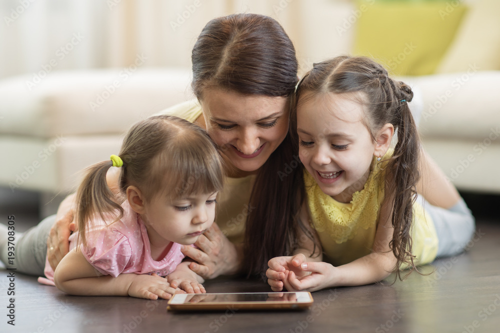 Happy woman and her children using digital tablet on floor at home Happy woman and her children using digital tablet on floor at home