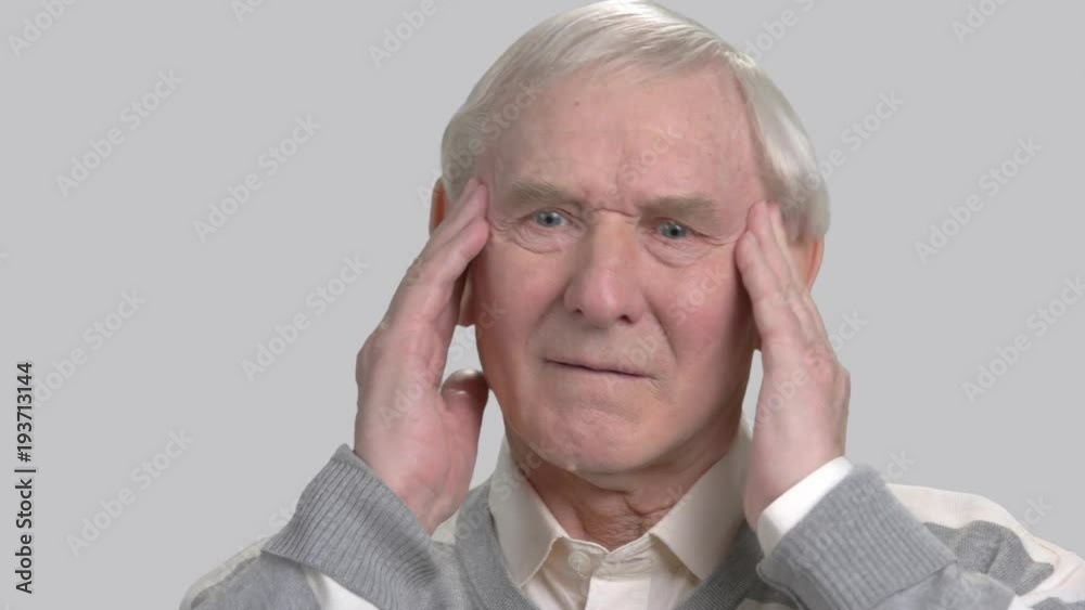 Caucasian pensioner feeling pain in his temples. Old european man suffering from terrible headache, grey background. Pain and facial expression. Caucasian pensioner feeling pain in his temples. Old european man suffering from terrible headache, grey background. Pain and facial expression.
