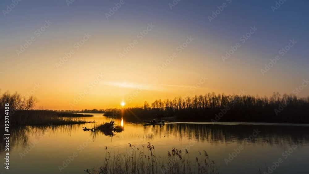 Autumn colors of beautiful sunset in Danube Delta. fisherman in a boat Autumn colors of beautiful sunset in Danube Delta. fisherman in a boat