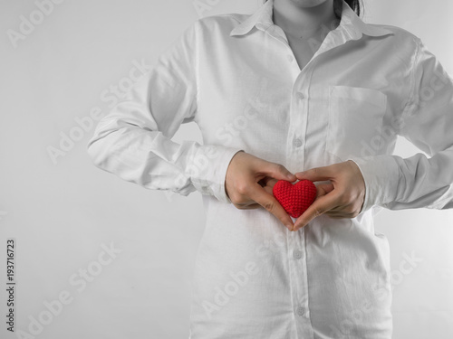 young woman in white shirt and hand hold red heart shape sign on isolated white background. concept of heart disease.protection.