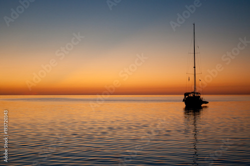A sailboat settling in for the night at a calm anchorage in the Berry Islands, Bahamas. The backside of the island chain provides wonderful views of the horizon at sunset. © Daniel