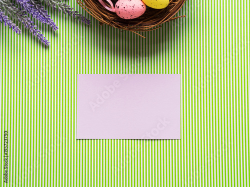 Easter background with Basket of decorative eggs, flowers and blank paper card. Copy space