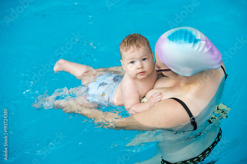 Young mother with her little daughter in the pool learning to swim