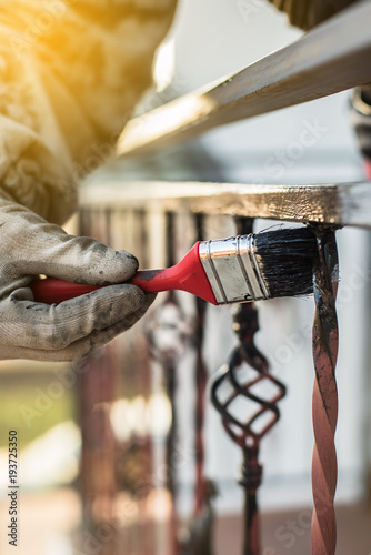 Covering forged railings by primer and paint, brush tool, rotection against rust, workflow, housework photo